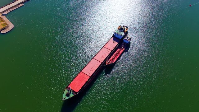 Bunkering operation or ship to ship transfer on green sea water with sun glint. Aerial view of small tanker alongside large cargo ship.