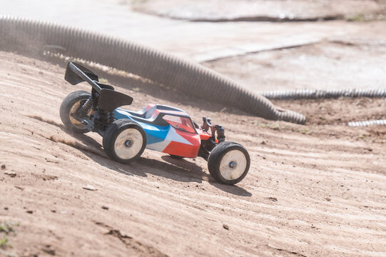 Radio-controlled car speeding on a dirt track, raising dust