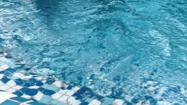 Clean swimming pool with clear blue water and sun reflections