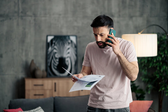 Man feeling financial stress talking on phone holding bills