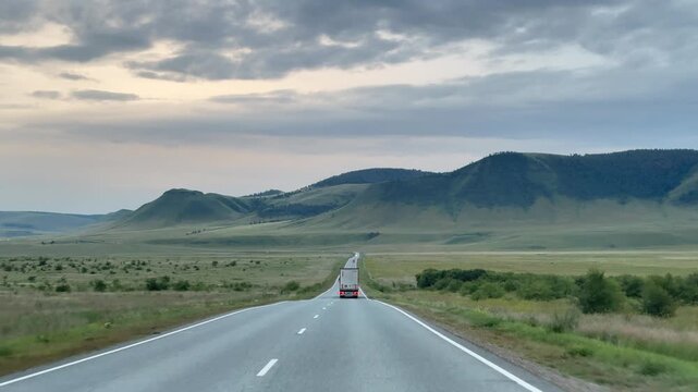 Open road through wide valley under cloudy sky Khakassia, conveying freedom, distance, solitude, travel, movement, and cinematic landscape vastness.