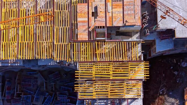 Detailed aerial shot of yellow wooden beams and formwork panels prepared for pouring concrete on a building structure. Top down view of construction site.