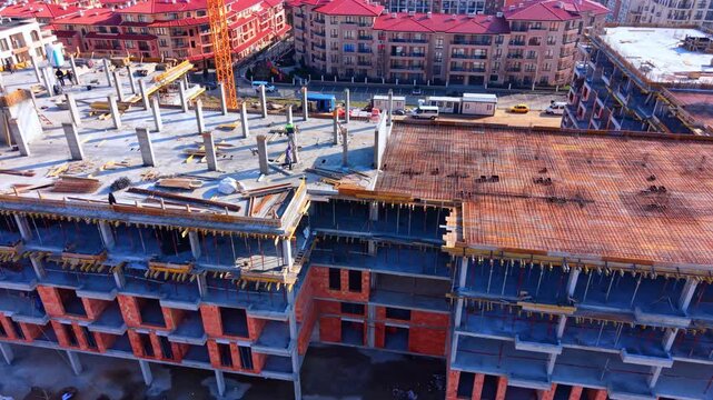 High angle shot showing red brick walls, concrete slabs, rebar, and support props of a modern residential project. Elevated view of multistory building under construction.