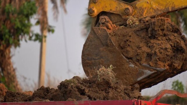 Excavator Bucket Loading Soil into Tractor at Indian Construction Site. Loading Soil into Tractor Trolley Construction India.