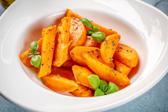 Roasted sweet potato wedges with basil in white bowl
