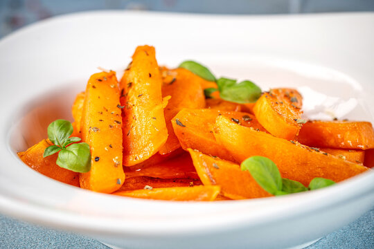 Roasted sweet potato slices with herbs in white bowl