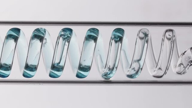 Glass spiral tube filled with blue liquid on white background.