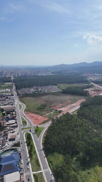 Drone registra rotat&oacute;ria urbana cercada por vegeta&ccedil;&atilde;o e edif&iacute;cios em Mogi das Cruzes no Alto Tiet&ecirc; paulista.