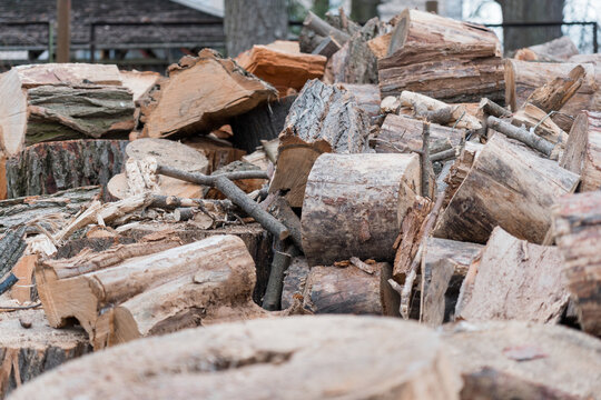 Pile Of Roughly Split Firewood Logs With Textured Bark And Fresh Cut Surfaces In Outdoor Rustic Setting Displaying Natural Brown Tones