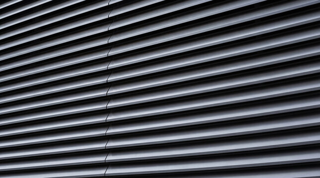 Gray louvered metal building facade. Abstract architectural pattern with horizontal parallel lines. Industrial city background for minimal design, screensaver or modern urban texture.
