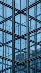 Obraz premium Modern glass skyscraper facade with geometric window pattern. Abstract architectural detail of office building exterior. Corporate city construction background for design projects.
