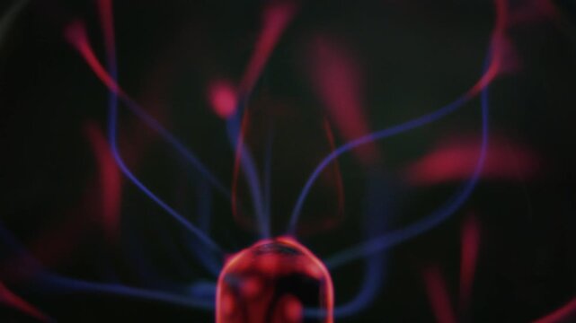 Plasma ball glowing, showing electric discharge and energy. Red and blue thunder light strands, on a dark background video loop