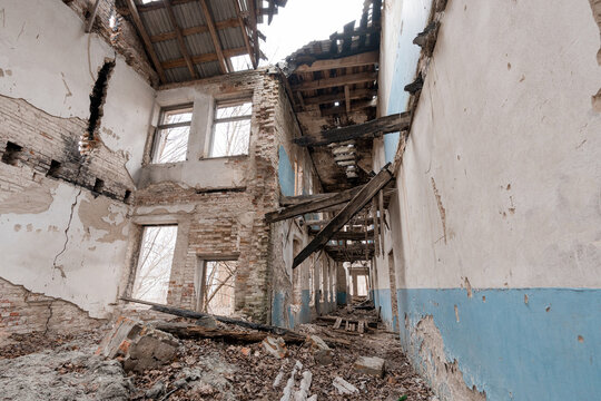 Dilapidated Abandoned Building Interior With Collapsed Roof, Exposed Brick Walls, Blue Paint Remnants And Debris Littered Floor In Derelict State Showing Decay And Neglect Over Time