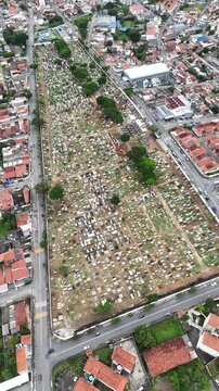 Vista a&eacute;rea de cemit&eacute;rio em Mogi das Cruzes com t&uacute;mulos organizados e &aacute;rea urbana ao redor destacando estrutura funer&aacute;ria e ocupa&ccedil;&atilde;o urbana