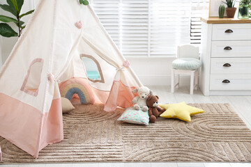 Toy wigwam with pillows, furniture and floral decor in room © New Africa