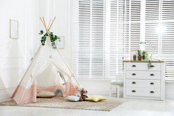 Toy wigwam with pillows, furniture and floral decor in room © New Africa
