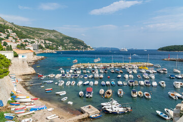 Small boats in Dubrovnik bay with clear blue Adriatic Sea and coastal landscape in Croatia, summer travel destination