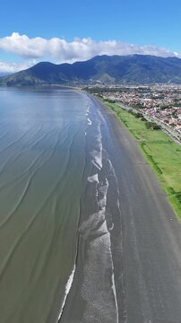 Imagem a&eacute;rea da praia do Porto Novo com mar calmo e areia extensa evidenciando paisagem natural e turismo no litoral paulista