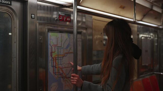 Woman pointing at transit map while standing in subway train