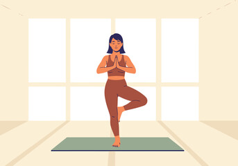 Fototapeta premium A serene woman practices tree pose in a bright, minimalist studio. She?s smiling, embodying wellness and balance. Focus on calm and mindful movement.