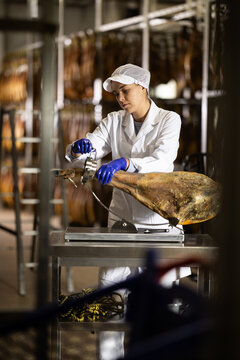 Girl places jamon on jamonero to cut it into appetizing pieces. Ham factory
