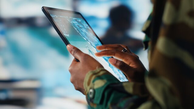 Soldier using warning system software on tablet in control room to monitor incoming enemy aerial attacks. Army agent maintains air space superiority with radar during armed conflict, close up