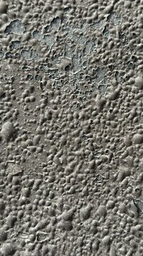 Uniflex rolled roofing closeup texture revealing granular asphalt surface with gritty granules, weathered bubbles, polymer coating.