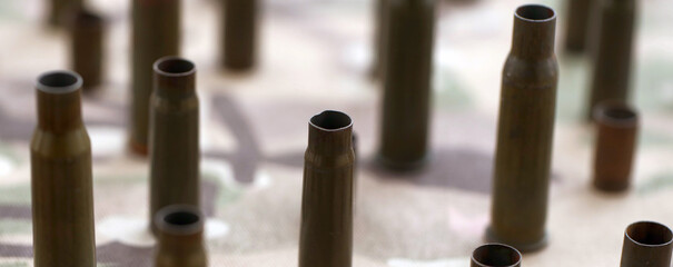 Fototapeta premium Big amount of shells cartridges from assault rifle bullets on old camouflage fabric