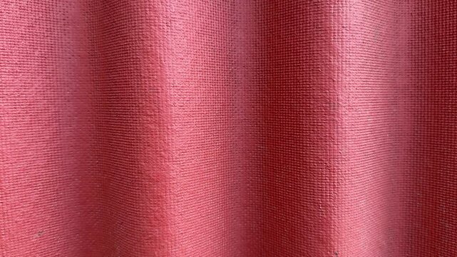 Red ondulin roofing close up corrugated. Fine grain bitumen surface with repeating waves, sunlight highlights, weatherproof.