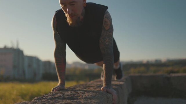 Tattooed athletic man doing push ups outdoors