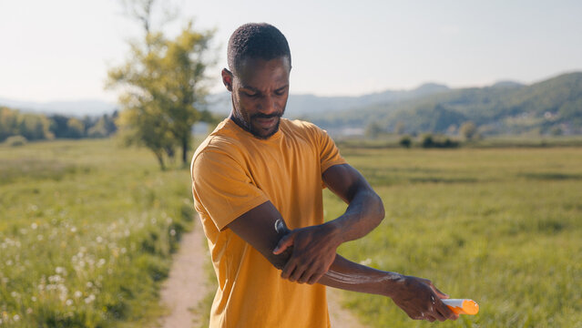 Man applying sunscreen before sun exposure on a walk in nature, covering all exposed arm areas. Healthy lifestyles concept.