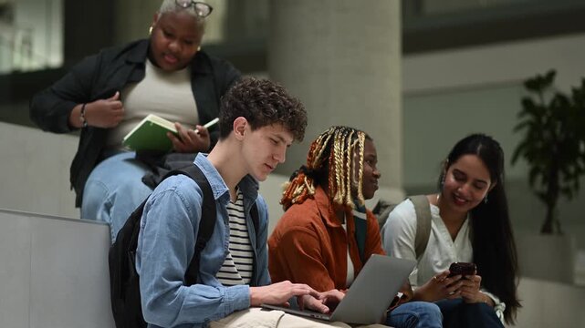 Diverse students collaborating with laptop and smartphone in a modern university campus hall
