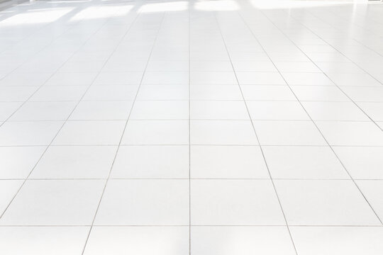 Clean, pristine and well maintained white ceramic tile floor in perspective view, bright smooth surface with subtle reflections. Ideal for product display backgrounds, durability and clean aesthetic.