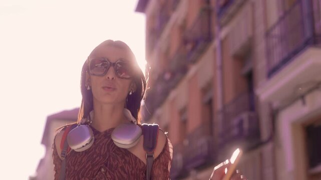 Stylish young woman happily dancing on city street