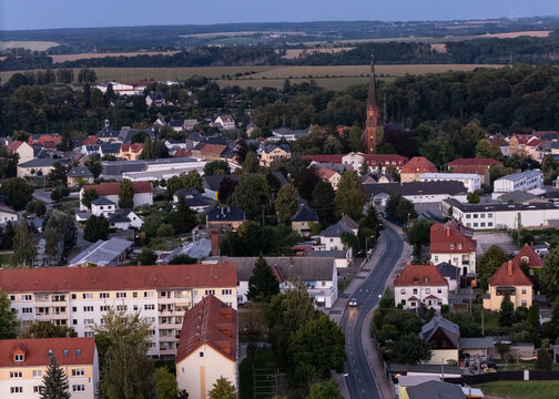 An aerial view of the peaceful small town "Hainichen" in Saxony Germany; featuring red-roofed houses, lush green trees, and a prominent gothic-style church tower. Hometown of the Poet "Gellert"