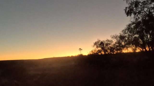 Time-lapse of a golden sunset in the Karoo with a windpump silhouetted on the horizon. 4K video.