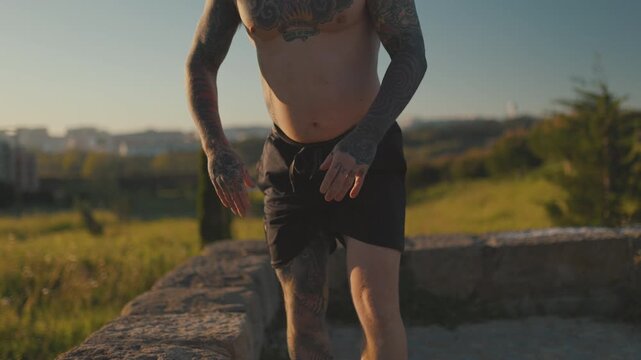 Tattooed man training outdoors during sunset