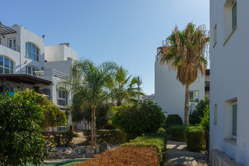 Fototapeta premium Sunny day in a tranquil residential complex with lush gardens and palm trees.