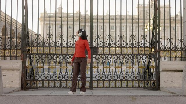 Joyful woman dancing with headphones in Madrid royal palace