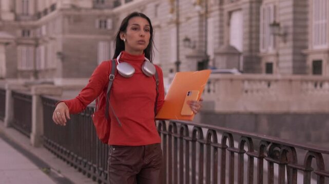 Young female university student happily walking and dancing in the city