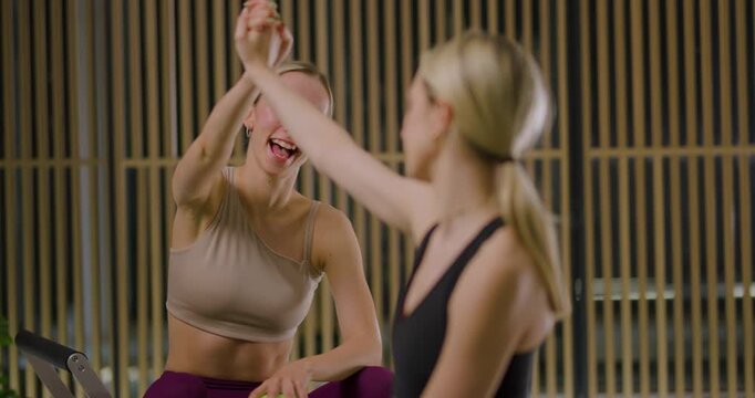 Two fitness enthusiasts are sharing valuable workout tips in a serene studio. Their interactions focus on effective techniques and creating a motivating atmosphere