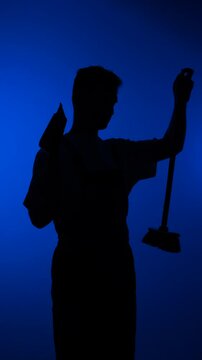 Vertical video cleaner man silhouette holding a dustpan and broom against a vibrant blue background, representing cleaning service and hygiene concepts