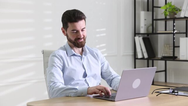 Handsome businessman working on laptop at wooden desk in office