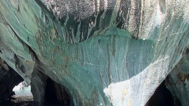 Witness stunning Marble Caves of Patagonia, natural wonder carved by water and time. Sunlight illuminates vibrant blue and gray rock formations inside grottoes, revealing their unique beauty.