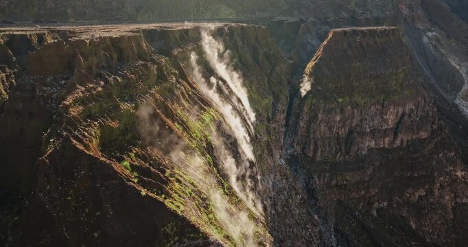 Steep caldera walls on Ambrym Island volcano with deep chasm and steam rising from crater, highlighting island active geothermal system and rugged geology. Travel to Vanuatu. Aerial view drone flight