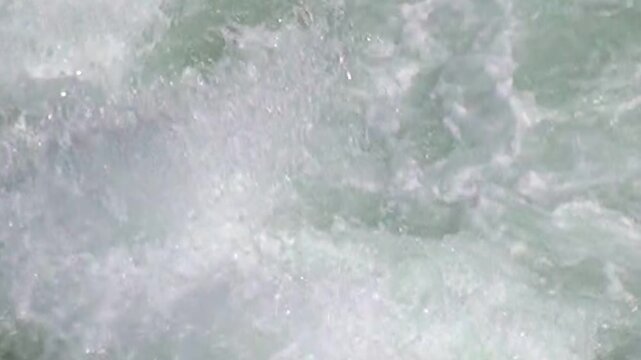 Turquoise water thrashes and foams as it rushes over rocks and through the riverbed. The fierce glacial river churns in Patagonia, showing its powerful current.