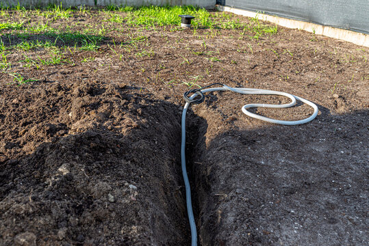 Digging garden trench for underground electrical cable conduit