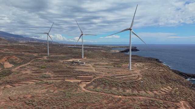 Aerial drone footage of a wind farm in Tenerife, Canary Islands, featuring rows of wind turbines generating renewable energy across a rugged volcanic landscape