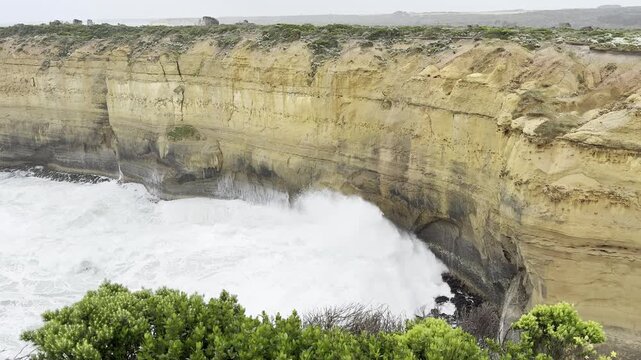 Powerful ocean waves crashing against the dramatic cliffs at the Loch Ard Gorge viewpoint near the Twelve Apostles on the Great Ocean Road, Victoria, Australia