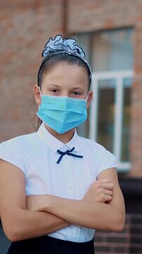 Outdoor portrait of teenage schoolgirl wearing a medical mask in an empty schoolyard